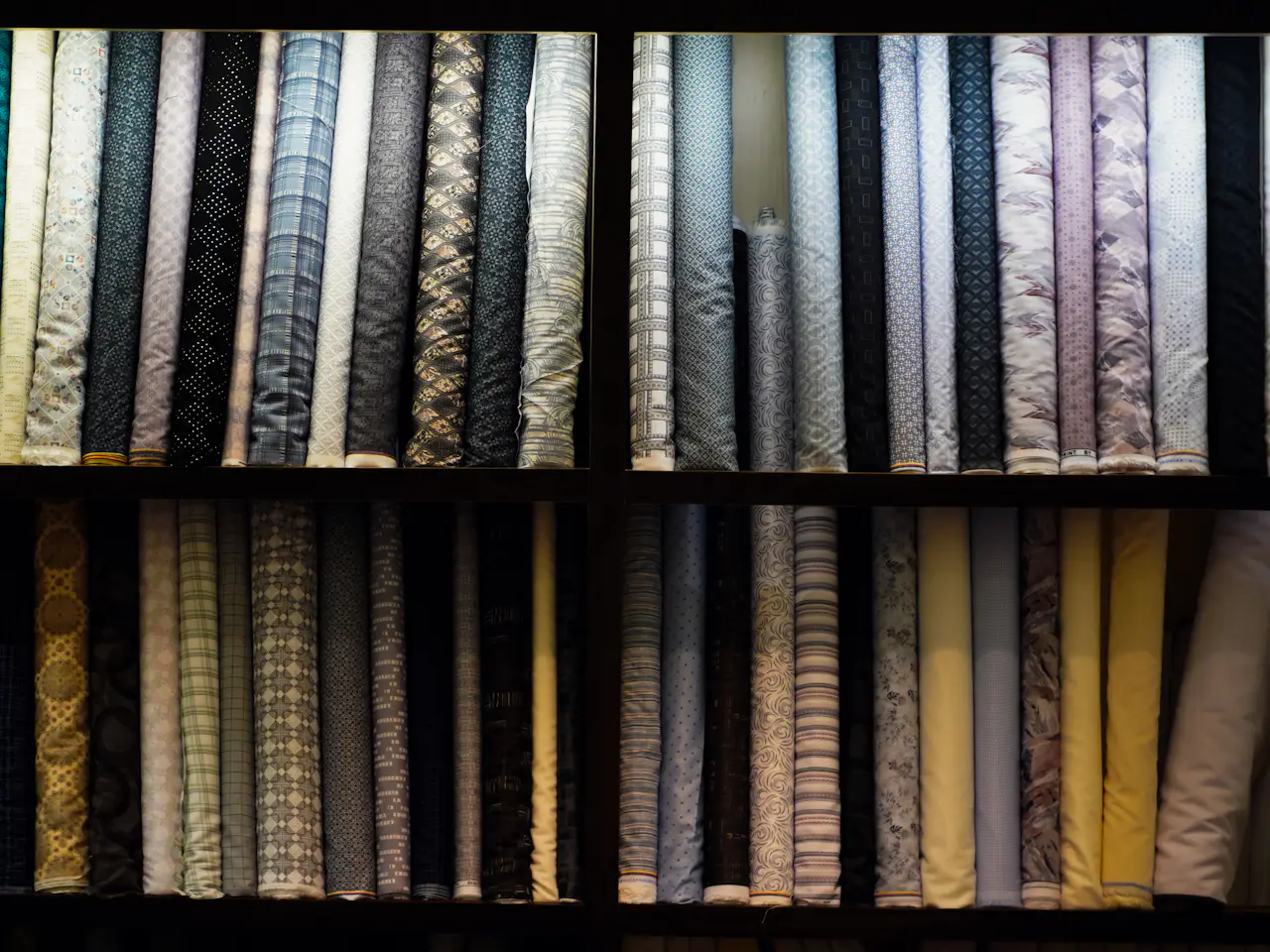 Rolls of patterned shirting stacked on warehouse shelves
