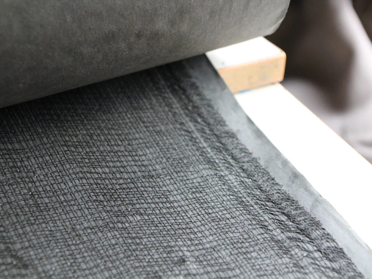 Dark grey suiting cloth laid flat on a pale surface