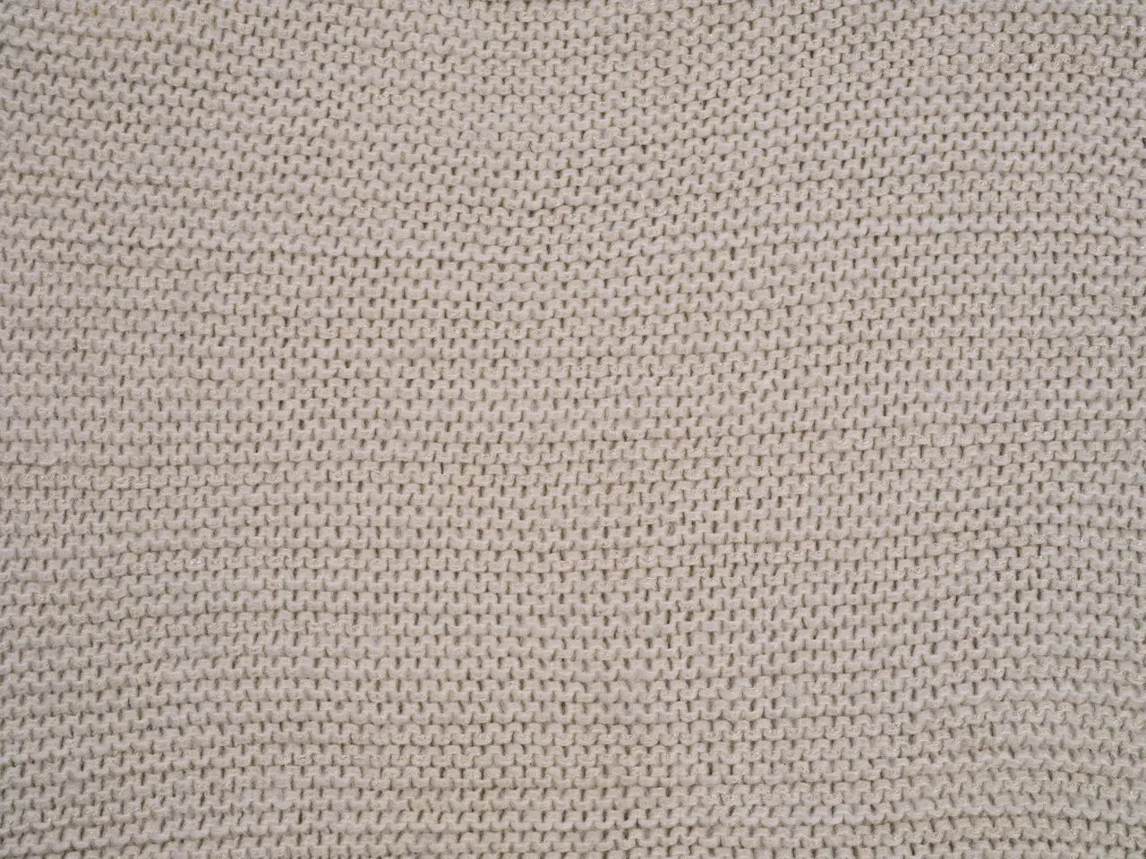Knitted fabric in a natural tone showing the loop structure of the stitch