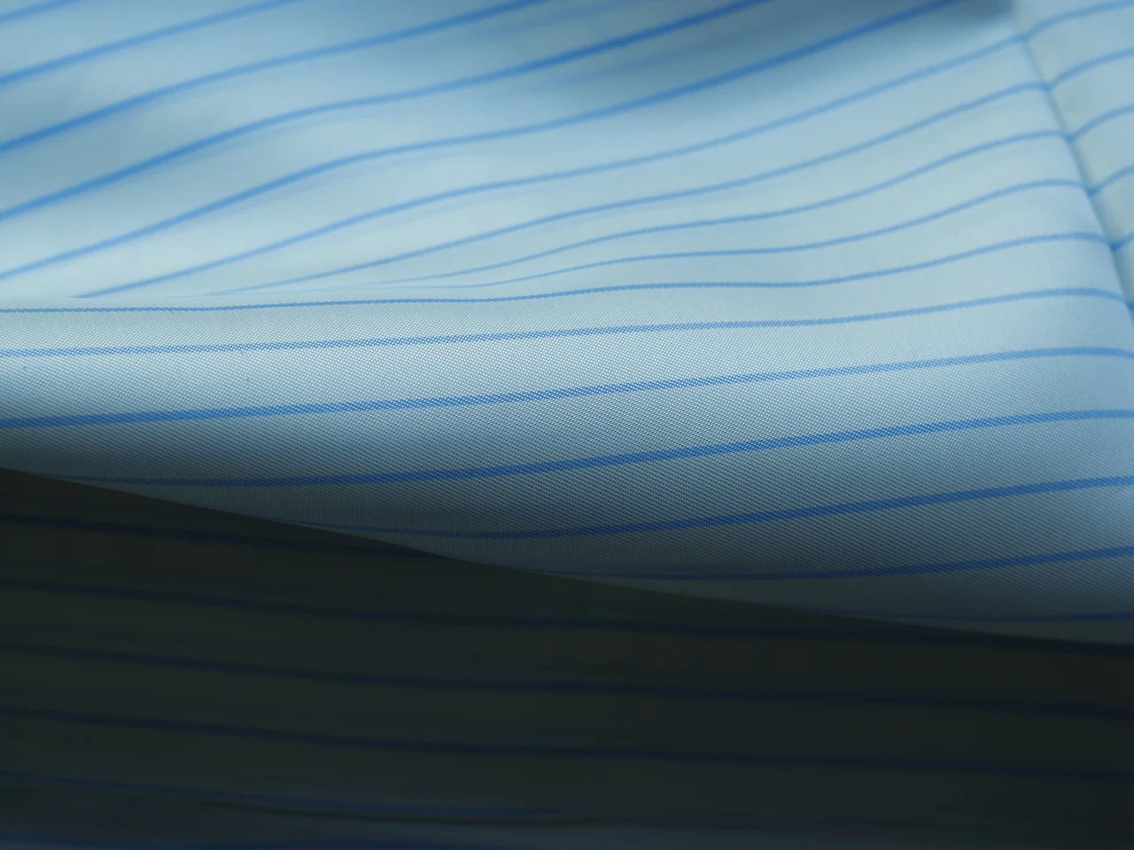 Pale blue striped shirting cloth folded to show the weave