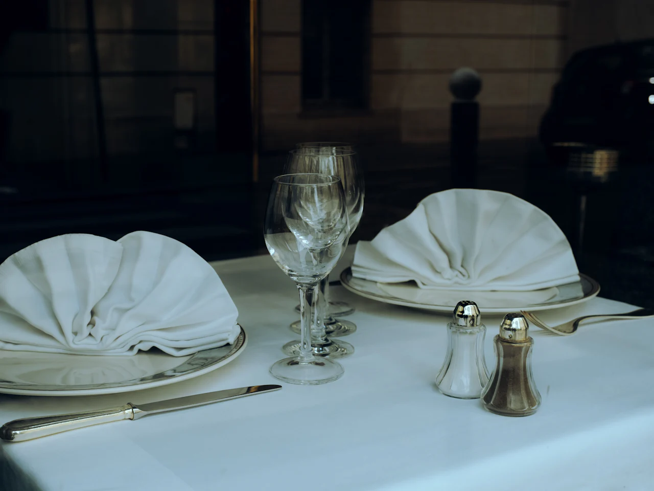 A restaurant table laid with white linen, glassware and silverware